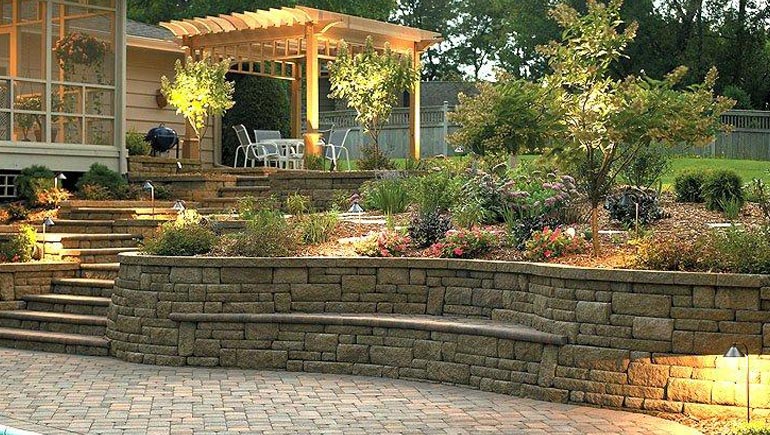 A well lit retaining wall with a gazebo on top of it.